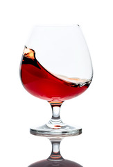 Splash of cognac in glass, isolated on white.