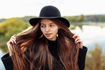 Close-up portrait of young beautiful fashionable woman in black hat, long hair