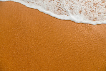 Foam of the ocean surf waves on beach sand.