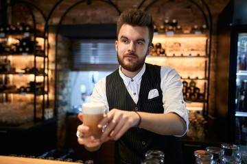 young handsome barmen giving beverage to clients while standing behind the table. close up photo, business, sale, discount