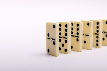 Domino's effect composition of a multiple domino bones placed in a row in white background.