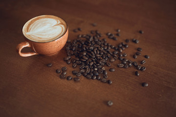 Composition with white cup of coffee and many beens is on the wooden table of the coffee shop, top view photo.coffee lover