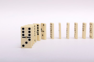 Domino's effect composition of a multiple domino bones placed in a row in white background.
