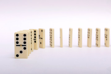 Domino's effect composition of a multiple domino bones placed in a row in white background.