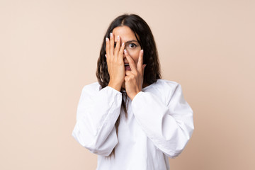 Young woman over isolated background covering eyes and looking through fingers