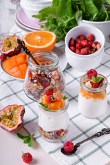 Natural yogurt, granola and mashed passion fruit and mango layered in a glass jar. Breakfast idea