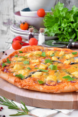 Round pizza with anchovies, mozzarella cheese and tomato sauce garnished with fresh parsley on white table