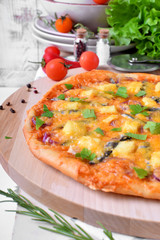 Round pizza with anchovies, mozzarella cheese and tomato sauce garnished with fresh parsley on white table