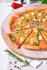 Round pizza with anchovies, mozzarella cheese and tomato sauce garnished with fresh parsley on white table