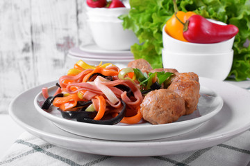 Multicolored pasta and meatballs garnished with parsley served on the white ceramic plate