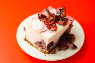 Japanese cheesecake with cherry sauce and fresh cherries on the ceramic plate and red background