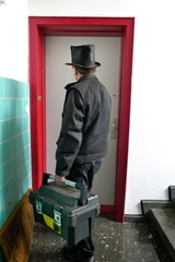 Chimney sweep stands in front of a front door in work clothes. Rear View. Germany