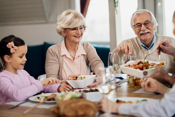 Happy grandparents having lunch with their family at dining table.