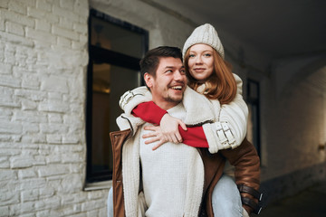 Fototapeta premium ginger attractive girl posing to the camera while sitting on the back of her positive man, close up photo