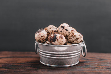 quail eggs in a small metal pan on a wooden background