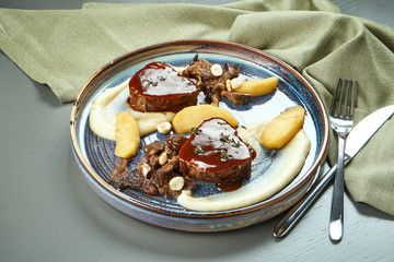 Beautiful and juicy steak from calf (beef) tenderloin with sauce garnished celery cream puree on a blue plate on a wooden background.