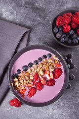 Smoothie bowl with berries and muesli on the gray table. Top view. Copy space.