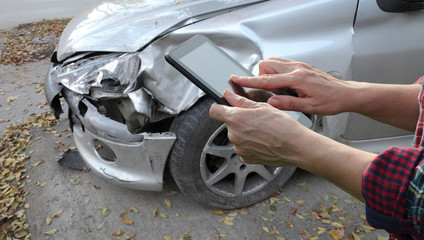 Damaged car inspection, female hands typing to tablet, insurance agent or worker 