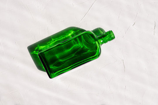 Empty Green Bottle With A Shadow From Sunshine On A White Textured Background.