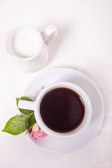 A cup of tea and pink roses on the white table. Top view.