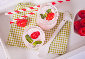 Two portions natural homemade yogurt in a glass jar with fresh raspberry. Breakfast concept. Top view.