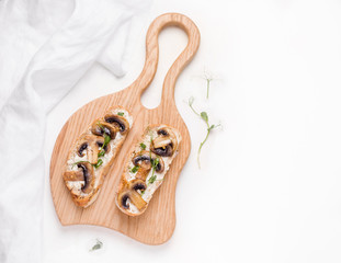 vegetarian sandwich with cheese, fried mushrooms and micro greens on a wooden board on a light background. copy space. close-up