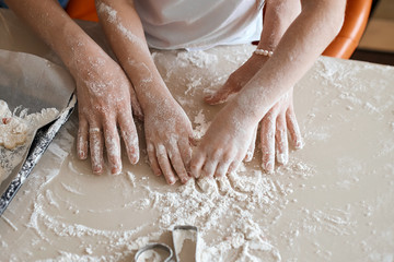 Fototapeta premium woman and girl's hands going to kneading the dough. close up cropped photo.household chores. lifestyle, free time, spare time