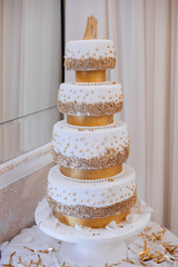 White and golden wedding cake. Beautiful wedding cake detail - traditional sweets to Bride and Groom. Delicious cake for a special day