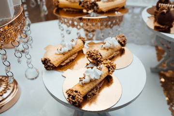Wedding decoration with colorful cupcakes, eclairs, souffle, meringues, muffins and macarons. Elegant and luxurious event arrangement with sweets. Wedding dessert table