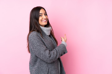 Young brunette woman over isolated pink background pointing back