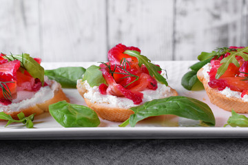Trout Gravlax on the slices of white bread with ricotta topped with greenery against the white background. Nordic cuisine meal