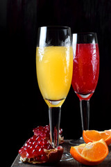 Yellow and red cocktails with champagne and fruit syrups in champagne glasses against the black background