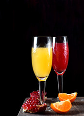 Yellow and red cocktails with champagne and fruit syrups in champagne glasses against the black background