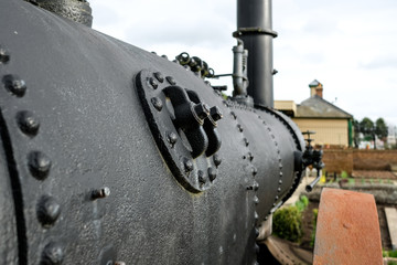 Shallow focus of a boiler plate and rivets seen on a very old, steam boiler. Once an agricultural tractor, now on show for exhibition purposes.