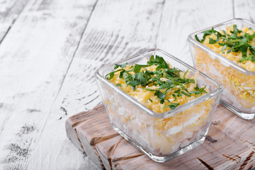 Layered salad with chicken, pineapple and cheese served in portion bowls topped with fresh herbs