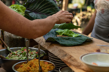 A closeup and selective focus view as organic food is served on large green collard leaves during a festival promoting healthy lifestyle and earth
