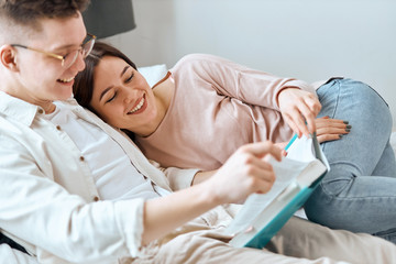 young man and woman in casula clothes resting in the bedroom, reading funny stories, comedies, favourite pastime,close up side view photo