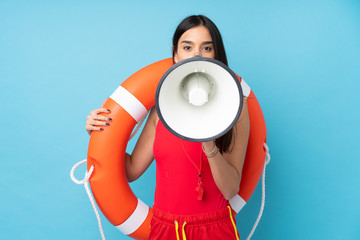 Lifeguard woman over isolated blue background with lifeguard equipment and shouting through a...