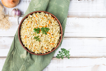 Stewed side dish of brown rice in a bowl on a green linen napkin. Traditional national cuisine. The image has a copy space