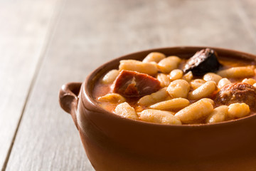 Typical Spanish fabada asturiana in crockpot on wooden table. Close up