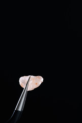 Macro shot of Himalayan salt crystal. Metal tweezers, black background, high resolution, hard light