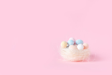 Fototapeta na wymiar Easter. Nest with multi-colored festive Easter eggs on pink background. Flat lay with copy space.