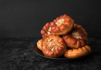 Fried peremyachi, belyashi, pies on a black background. Traditional Russian pies. Russian, Bashkir and Tatar cuisine. Copy space.