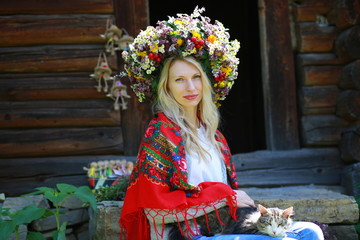  girl in floral wreath and scarf in Ukrainian ethnic style enjoy the aroma of flowers