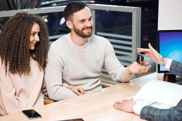 Obraz premium young elegant man in fashion suit giving the keys to a couple, business, trade, close up photo, car selling, car exchanging