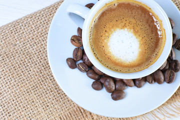 Maquiatto coffee cup with coffee beans on white wooden background