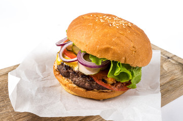 Tasty homemade burger consisting of bun, cheese, salad, red onion and tomato