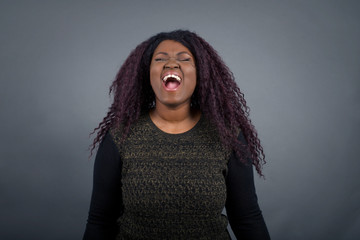 Stressful African American woman screams in panic, closes eyes in terror, keeps hands on head,...