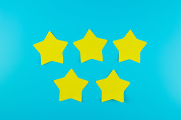 five star yellow paper note on blue background with copy space for text. Customer reviews, feedback, rating, ranking and service concept.