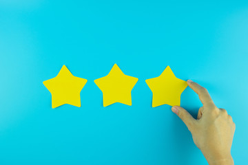 customer holding three star yellow paper note on blue background. Customer reviews, feedback,...